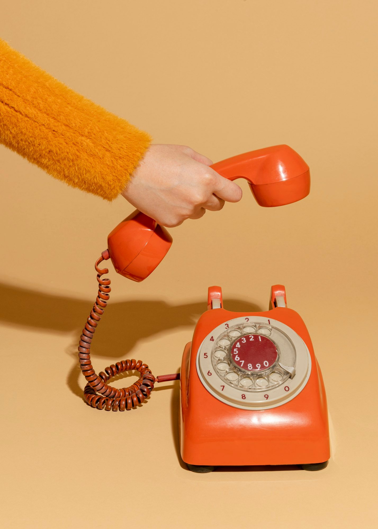 Persona contestando a la llamada de un teléfono antiguo.